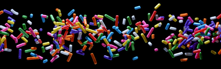 Small sprinkle colorful sugar candies flying sweet food. isolated on a black background	