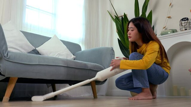 Happy Asian woman using vacuum cleaner dust while cleaning floor at home, Female housekeeper, housewife cleaning in living room, housework people lifestyle