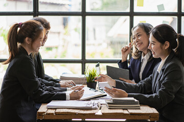 Group of young Asian businessmen discussing and planning their work happily and happily. At the company office presenting a chart in a business seminar with a colleague.