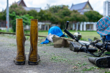 A dirty yellow rubber boots on a curbside with other gardening tools