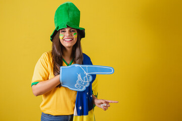Woman supporter of Brazil, World Cup 2022, pointing with foam finger to the right.