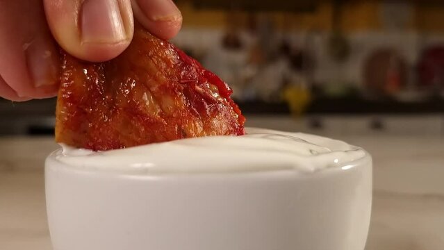 dipping buffalo wings into sauce, close up