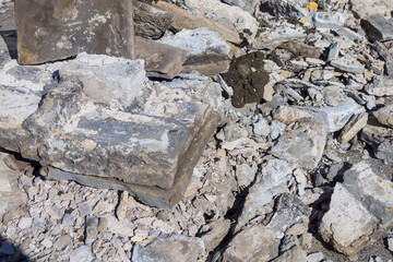 Construction debris made of broken stone and concrete tiles lies in pile on street on summer day. Background.