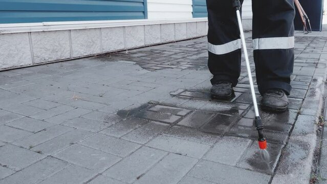 Video 4k. Worker treats surface of sidewalk with herbicides and chemicals from weeds and vegetation. Close-up of the workflow. The lower point of the survey. Services for spraying the joints of paving