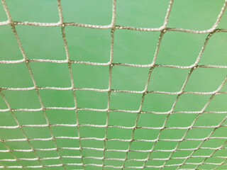 tennis net's white nylon strings and light green tennis court on background in full frame shot