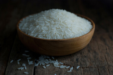 Jasmine rice in a wooden bowl placed on a rustic wooden floor.