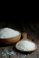 Fototapeta na wymiar Jasmine rice in a wooden ladle and in a wooden bowl placed on a rustic wooden floor.