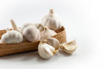 Several heads of garlic are placed in a wicker container. and put on a white background.
