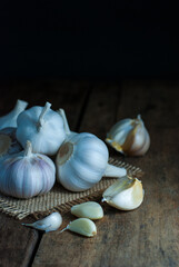 Several heads of garlic put on sackcloth on a rustic wooden floor.
