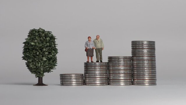 Miniature people and the concept of an aging society. A miniature old couple standing on a pile of step coins.
