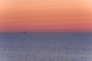 Naklejka na ściany i meble 能登半島で見た夕焼けに染まる日本海を進む貨物船の情景＠石川