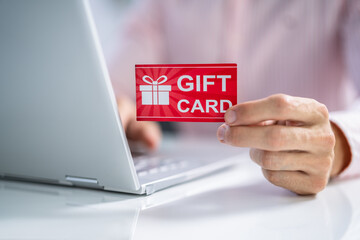 Man Holding Red Gift Card While Typing