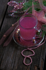 pink berry kissel (jelly) in a transparent glass mug on an old dark wooden table encircled by vintage jewelry. Russian traditional berry drink, national cuisine