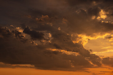 A beautiful sunset with gold, red, yellow and orange sunlight passing through many clouds of different hues. Horizontal photo. Nature. Sky. Cloudy. Background.