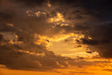 A beautiful sunset with gold, red, yellow and orange sunlight passing through many clouds of different hues. Horizontal photo. Nature. Sky. Cloudy. Background.
