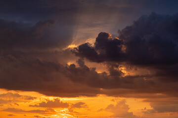 A beautiful sunset with gold, red, yellow and orange sunlight passing through many clouds of different hues. Horizontal photo. Nature. Sky. Cloudy. Background.