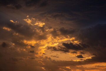 A beautiful sunset with gold, red, yellow and orange sunlight passing through many clouds of different hues. Horizontal photo. Nature. Sky. Cloudy. Background.