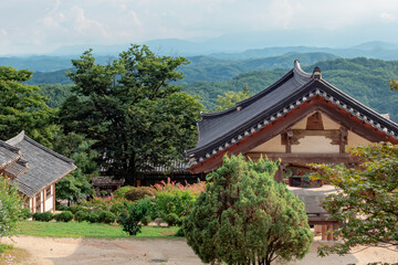 Fototapeta na wymiar Traditional Korean architecture and lush green forest and mountains at Buseoksa Buddhist temple complex in South Korea on a cloudy day 