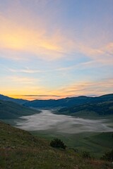 Fototapeta na wymiar Fog Filled Valley in the Mountains of Italy at Sunrise