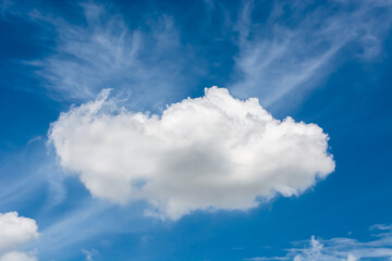 a bright blue sky with a large, fluffy white cloud in the center. There are wispy white clouds in the background.