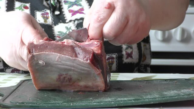 the cook cuts raw deer meat with a knife. healthy food concept