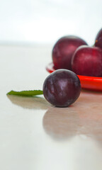 Plums in a red bowl