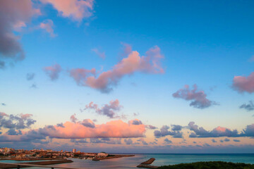 Beautiful sunset sky with orange and blue clouds floating, with some buildings on Ishigaki island,...