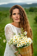 Naklejka na ściany i meble A middle-aged woman holds a large bouquet of daisies in her hands. Wildflowers for congratulations