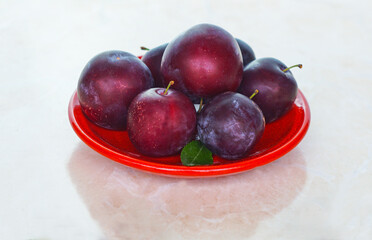 Plums in a red bowl