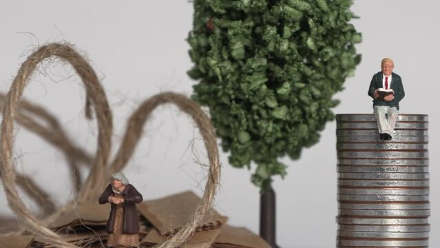 The concept of the gap between rich and poor. Business concept with piles of coins and miniature people.
