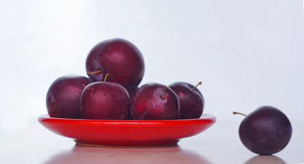 Plums in a red bowl