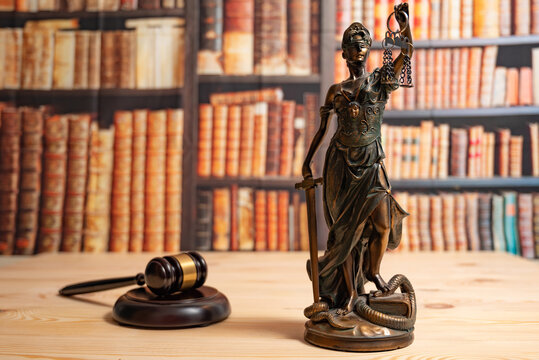 Lawyer office. Statue of Justice, scales and Judge's gavel against the backdrop of a wall of books or a library . Legal law, advice and justice concept