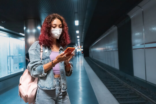 Asian girl wears a facial respiratory mask during the Covid-19 coronavirus pandemic and looks at the route of the trip to the place in the smartphone app - Powered by Adobe