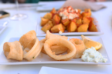 squid rings, lemon juice and potato with garlic sauce aioli and tomato ketchup on square plate