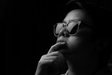 Fototapeta na wymiar Asian man wearing sunglasses in the dark, black and white tone
