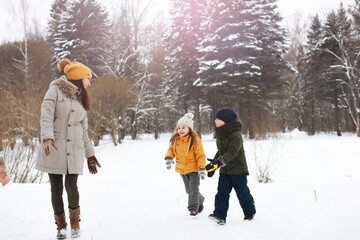 Fototapeta na wymiar Happy family playing and laughing in winter outdoors in the snow. City park winter day.