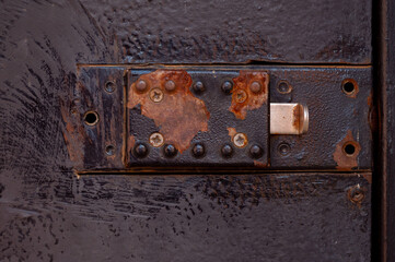 Old Rusted Technical Hatch With A Manual Lock, Latch. Red Rust Spots On Black Paint. 
Conceptual Background. Close Up.