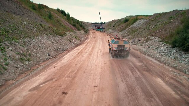 Old water truck spraying dusty road in quarry. Heavy industrial equipment in mining industry. 