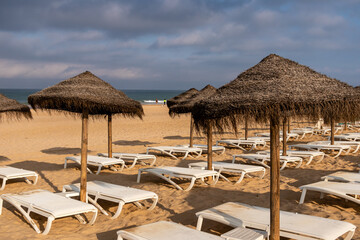 people walking along the beach of La Barrosa seen through the umbrellas of that beach