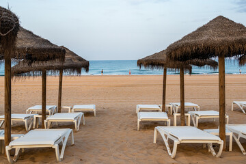 people walking along the beach of La Barrosa seen through the umbrellas of that beach