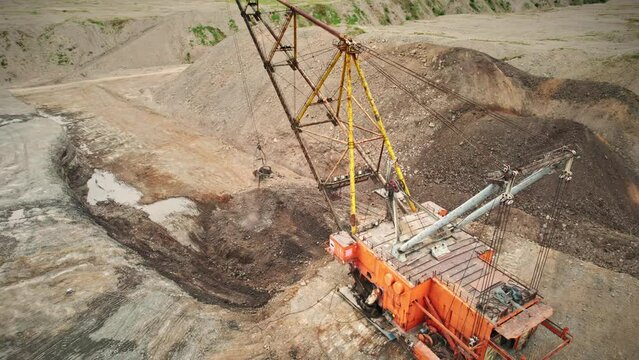 Huge dragliner excavator mining gold in an open pit. Aerial industrial quarry scene. Mining precious minerals. Pollution, environment and ecology concept