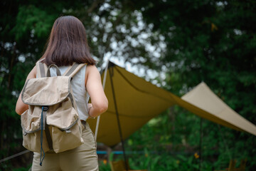 Back view. Asian woman camping on vacation. A beautiful female tourist loves to travel and go camping. Traveling to explore natural areas