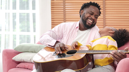 Happy family playing Guitar having fun together with little girl in modern living room. Funny active family carefree little kids with mum dad having fun laughing enjoy weekend at home