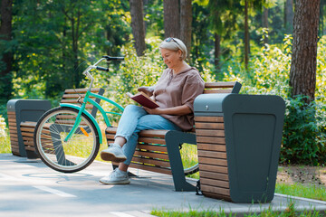 Dreamy modern old lady relaxing in city park. Pensive senior grey haired woman in casual sitting wooden bench outdoors. - Powered by Adobe