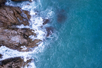 Obraz premium Aerial view of sea crashing waves White foaming waves on seashore rocks Top view Rocky coast mountain landscape view Nature background