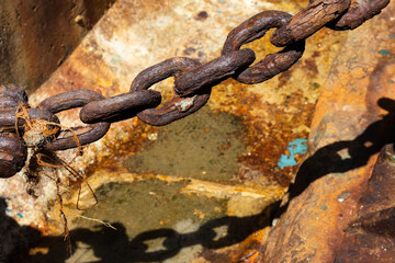 Chained.  Rusty metal chain hanging near a pier.  The chain casts a shadow.  Mui Wo, Hong Kong.