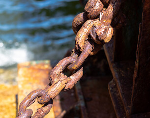 Chained.  Rusty metal chain hanging near a pier.  The sea is in the background.  Mui Wo, Hong Kong.