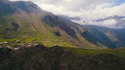 Obraz na płótnie Canvas scenic drone shot of the small settlement in the Caucasus mountains, Kazbegi, Georgia. High quality photo
