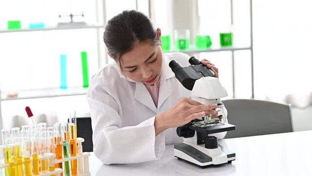 4K Woman scientist looking in microscope while working on medical research