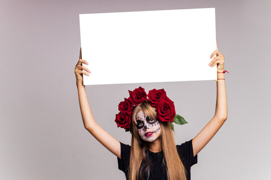 Portrait of young beautiful girl with make-up skeleton on her face and red roses on head